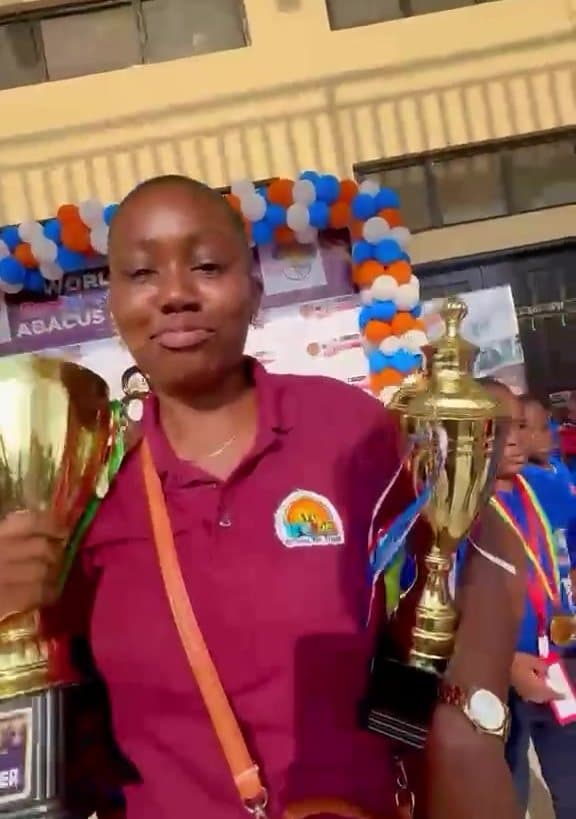 WWIS teacher holding abacus competition trophies