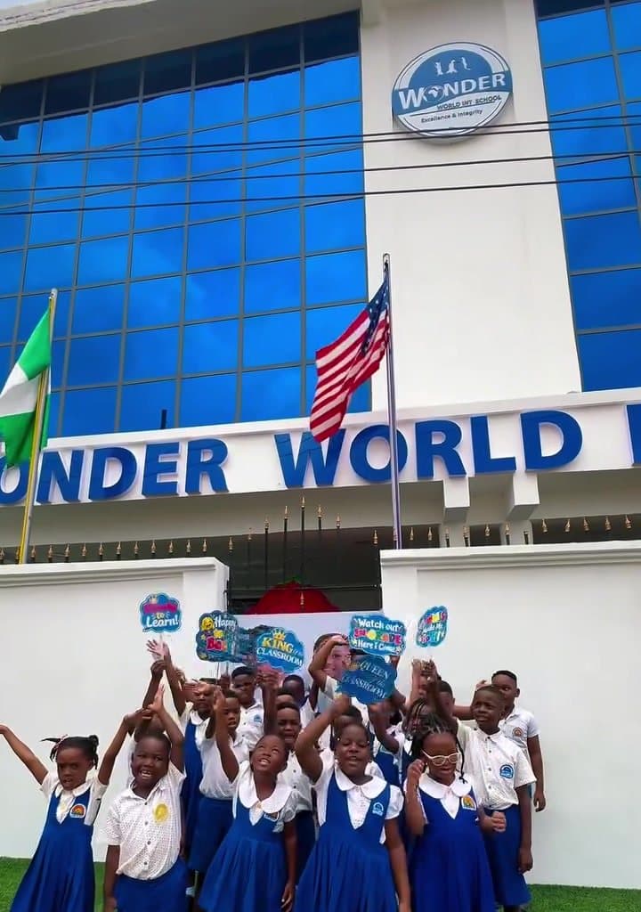 WWIS learners cheering in front of the Wonder World school building